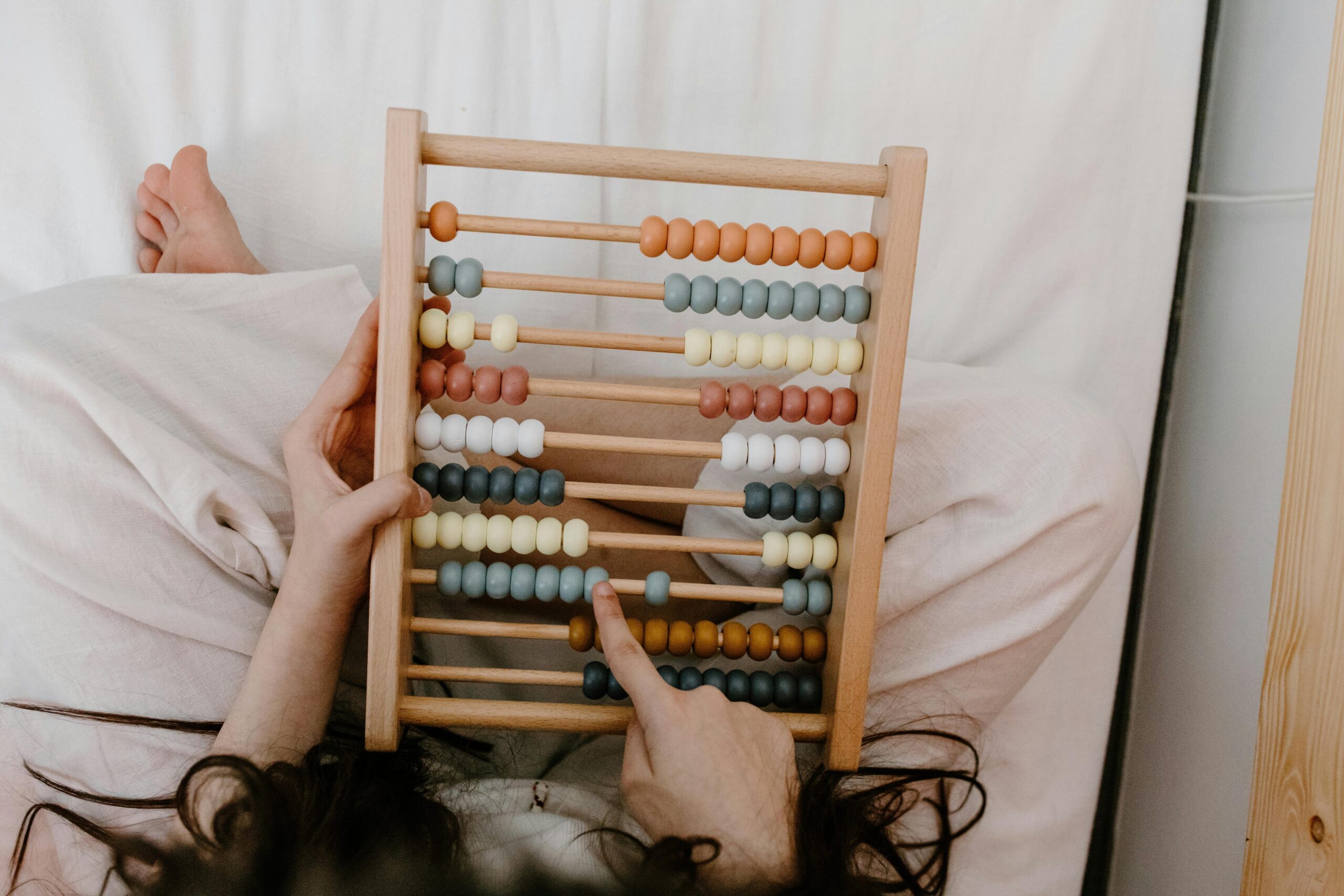A child playing with a colorful wooden abacus, focusing on math learning and development.